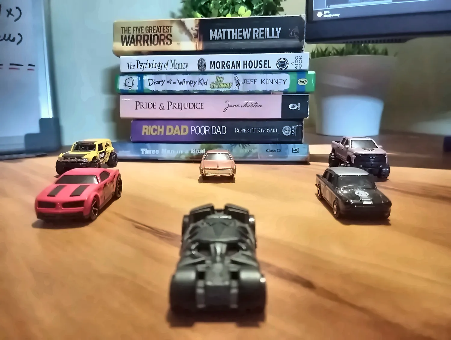 Hot Wheels lined up in front of my books